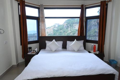 een slaapkamer met een wit bed en een groot raam bij Om Niwas Homestay in Shimla