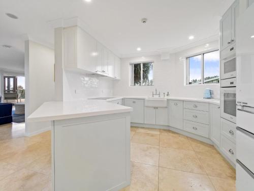a white kitchen with white cabinets and a sink at First Point Down by Discover Stradbroke in Point Lookout
