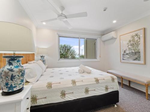 a bedroom with a large bed with a vase on it at First Point Down by Discover Stradbroke in Point Lookout