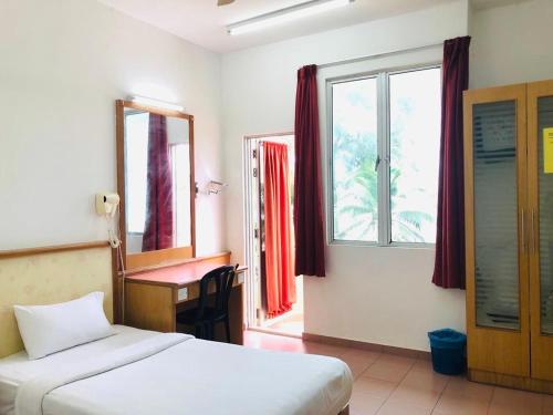 a bedroom with a bed and a desk and a window at Intan Beach Resort in Kuala Terengganu