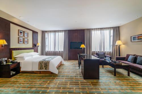 een hotelkamer met een bed en een bank bij Legend International Hotel in Huizhou