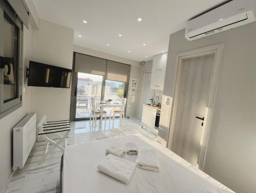 a white room with a white bed and a kitchen at BlueLine apartment 2 in Loutraki