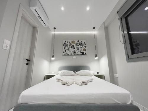 una camera da letto con un letto bianco con due asciugamani di BlueLine apartment 2 a Loutraki