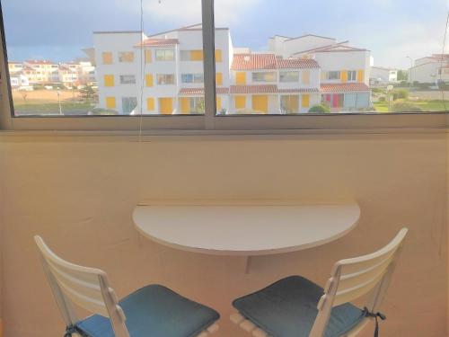 une table et deux chaises devant une fenêtre dans l'établissement Appartement familial à 2 pas de la plage, balcon, parking & commerces proches - FR-1-652-25, à Saint-Hilaire-de-Riez