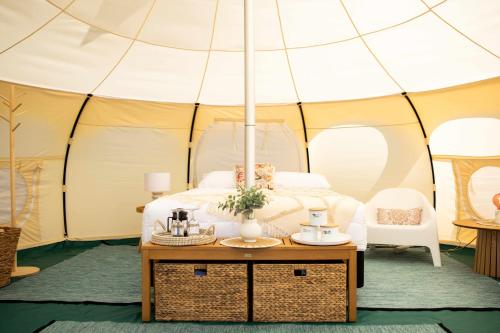 uma cama numa tenda com uma mesa na frente em Foxton Beach Holiday Park em Foxton Beach
