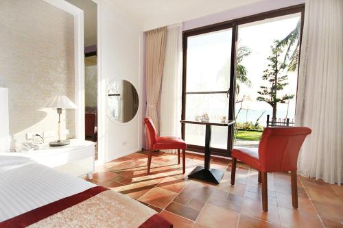 a bedroom with a bed and a desk and two chairs at Kenting Moli Bay Seaview Resort Hotel in Fangshan