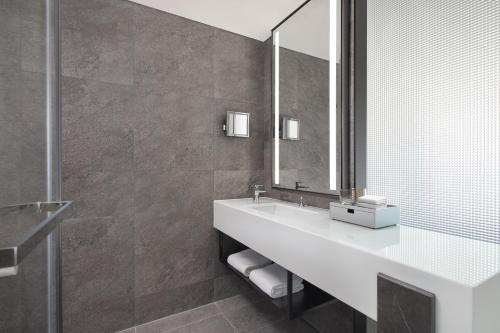 a bathroom with a white sink and a mirror at AC Hotel by Marriott Suzhou, Guan Qian in Suzhou