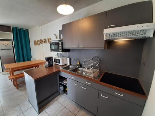 une cuisine avec des placards gris et un comptoir dans l'établissement Villa Patio Charmante, 2 Pas des Plages, Terrasse, Parking, Piste Cyclable - FR-1-239-892, à Capbreton