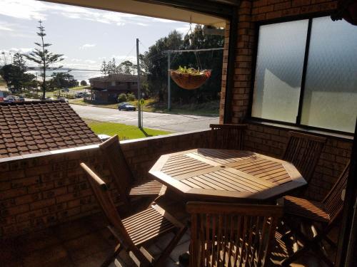 a wooden table and chairs on a porch with a window at Dalmeny Shores in Dalmeny