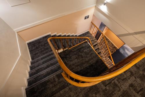 a spiral staircase with wooden railings in a building at Nightcap at Rex Hotel in Adelaide