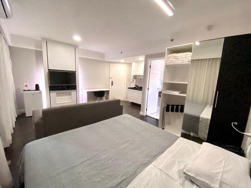 a white room with a bed and a kitchen at Flat Hotel de luxo em Moema, São Paulo in São Paulo