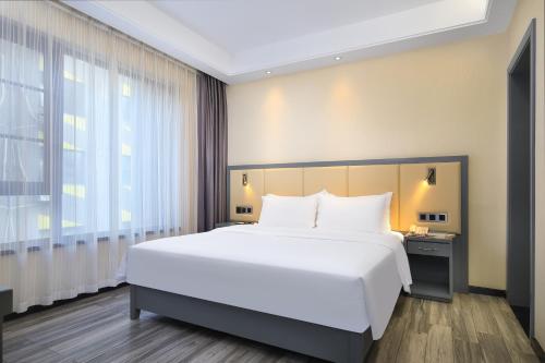 a bedroom with a large white bed and a window at Wing Hotel Guilin - Central Square in Guilin