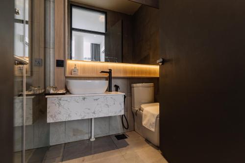 a bathroom with a sink and a toilet and a window at Impiana by Roxy Hotel in Kuching