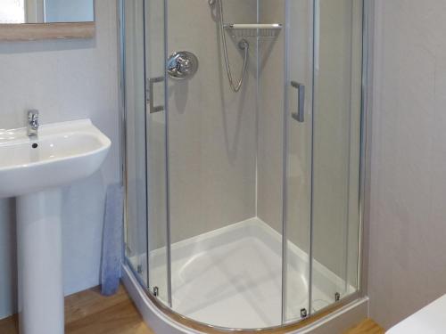 a shower with a glass door next to a sink at Barr Beithe Lower in Dallavich