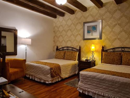a hotel room with two beds and a chair at Hotel Casa Divina Oaxaca in Oaxaca City