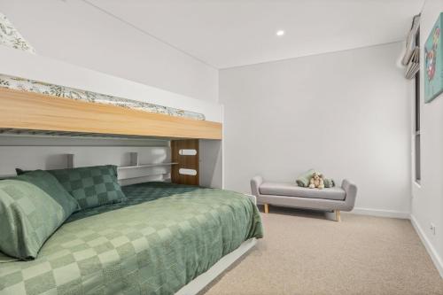 1 dormitorio con 1 cama verde y 1 sofá en Splash by Experience Jervis Bay, en Huskisson