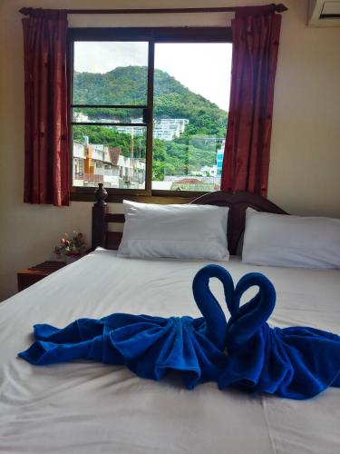 a bed with two blue hearts on it with a window at Kata Lina guesthouse in Kata Beach