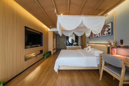 a bedroom with a large white bed and a television at AT NIGHT HOTEL Chengdu in Chengdu