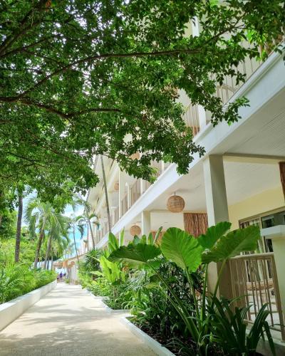 a sidewalk in front of a building with trees and plants at Elephant Beach Club & Resort Samui in Chaweng