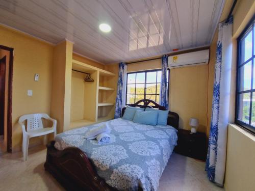 1 dormitorio con 1 cama, 1 silla y ventanas en Posada Seven Colours Ocean, en Providencia