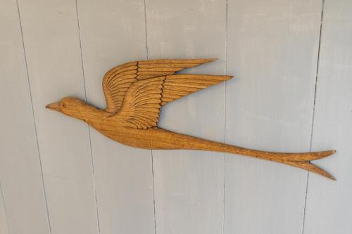 a wooden bird ornament hanging on a wall at Leu Boucan in Saint-Leu