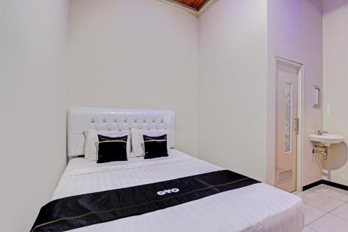 a bedroom with a large white bed with black pillows at Capital O 93244 Angkasa Inn in Tegal