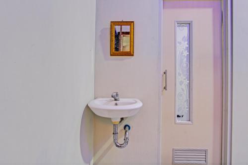 ein weißes Badezimmer mit einem Waschbecken und einem Spiegel in der Unterkunft Capital O 93244 Angkasa Inn in Tegal