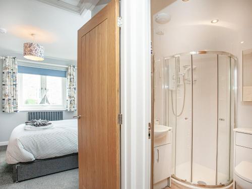 a bedroom with a bed and a shower and a bathroom at 6 Camelside in Wadebridge