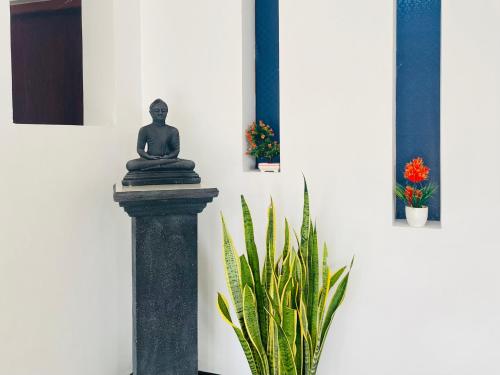 a statue sitting on a pillar next to a plant at Cinnamon City in Hikkaduwa