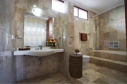 a bathroom with a sink and a toilet and a mirror at Guildwood Villa Bali in Sanur