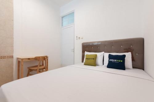 1 dormitorio con 1 cama blanca y 2 almohadas en Urbanview Hotel De Breeze Kemang Jakarta by RedDoorz, en Yakarta