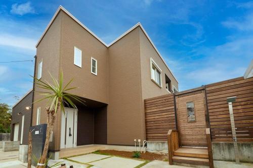 a brown brick house with a wooden fence at The Garden Villa 九十九里ー遊び充実の海近リゾート別荘を最大15名で一棟貸切 in Shirako