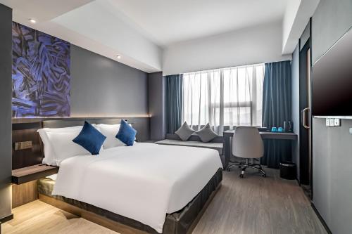 a bedroom with a large bed and a desk at Insail Hotels (Guangyuanxincun Jingtai Pedestrian Street Guangzhou) in Guangzhou