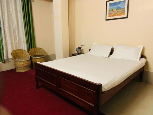 een bed met witte lakens en kussens in een kamer bij OYO Flagship Hotel West End in Darjeeling