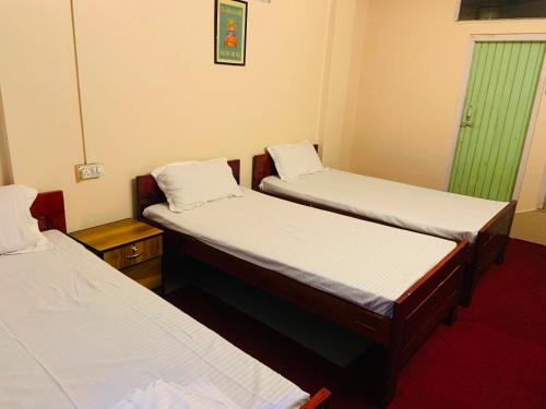 een kamer met 2 bedden en een groen raam bij OYO Flagship Hotel West End in Darjeeling