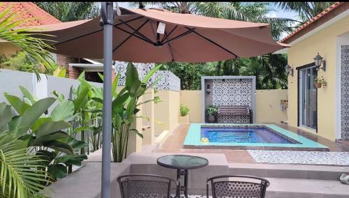 a patio with a table and an umbrella and a pool at Laman Zavilla Dhoma 2 in Bagan Lalang