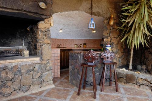 een keuken met twee houten krukken naast een stenen muur bij Castillo Lanzarote Villa 1 - Sleep in a Volcanic Cave in Tías