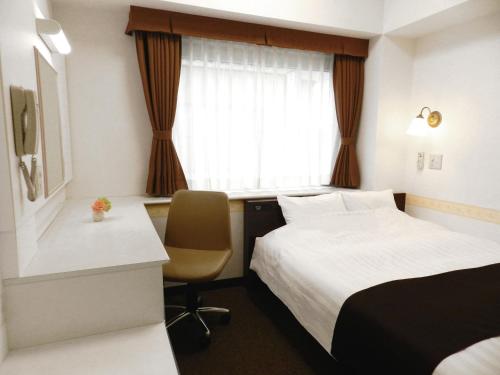 a hotel room with a bed and a desk and a window at Hotel Check In Shimbashi in Tokyo