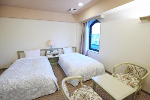 a hotel room with two beds and a window at Hotel Machida Villa in Machida