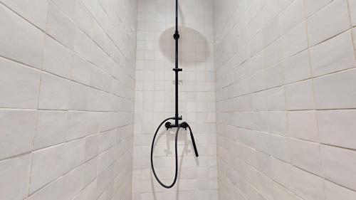 a shower with a hose in a white tiled bathroom at Le porte plume in Dole
