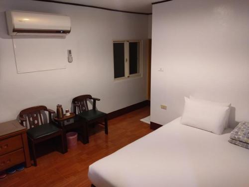 蘇澳鎮的住宿－金華冷泉溫泉旅館，一间卧室配有一张床、两把椅子和一张书桌