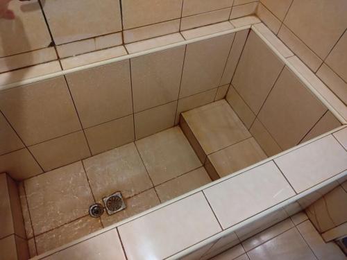 een lege douche in een badkamer met een tegelvloer bij Jinhua Cold Spring Hotel in Suao