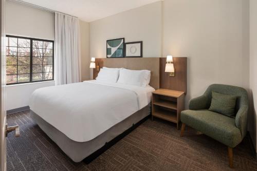 een slaapkamer met een groot bed en een stoel bij Staybridge Suites Minneapolis-Maple Grove, an IHG Hotel in Maple Grove