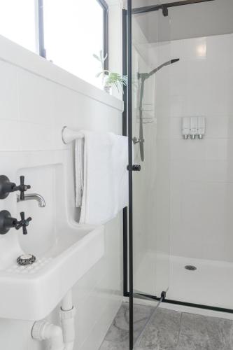 a white bathroom with a shower and a sink at Seafarers Cottage in Capel Sound