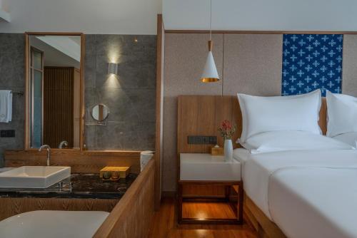a bedroom with a bed and a bathroom with a sink at Hong Long Jing Hotel in Dali