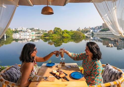 two women sitting at a table with glasses of wine at Moustache Udaipur Verandah in Udaipur