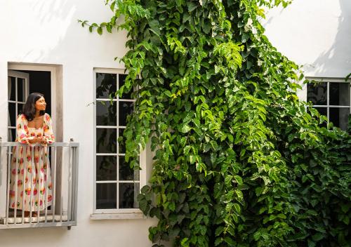 a woman standing on a balcony next to a ivy covered building at Moustache Udaipur Verandah in Udaipur