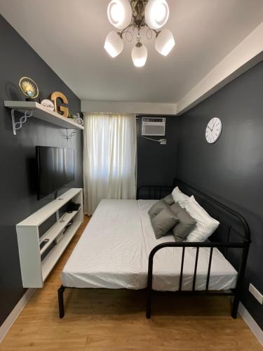 1 dormitorio con 1 cama y reloj en la pared en Condo Rentals in Arezzo - 1 Br Condo en Davao