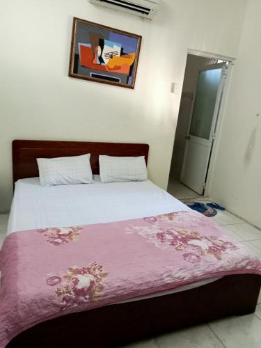 Un dormitorio con una cama con una manta rosa. en Nhà nghỉ MINH HOÀNG en Vung Tau