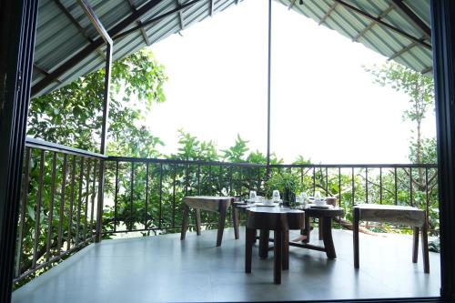 a patio with tables and chairs on a balcony at SaffronStays Aranya Vilas & Raanwaara Cottage in Āmbavna